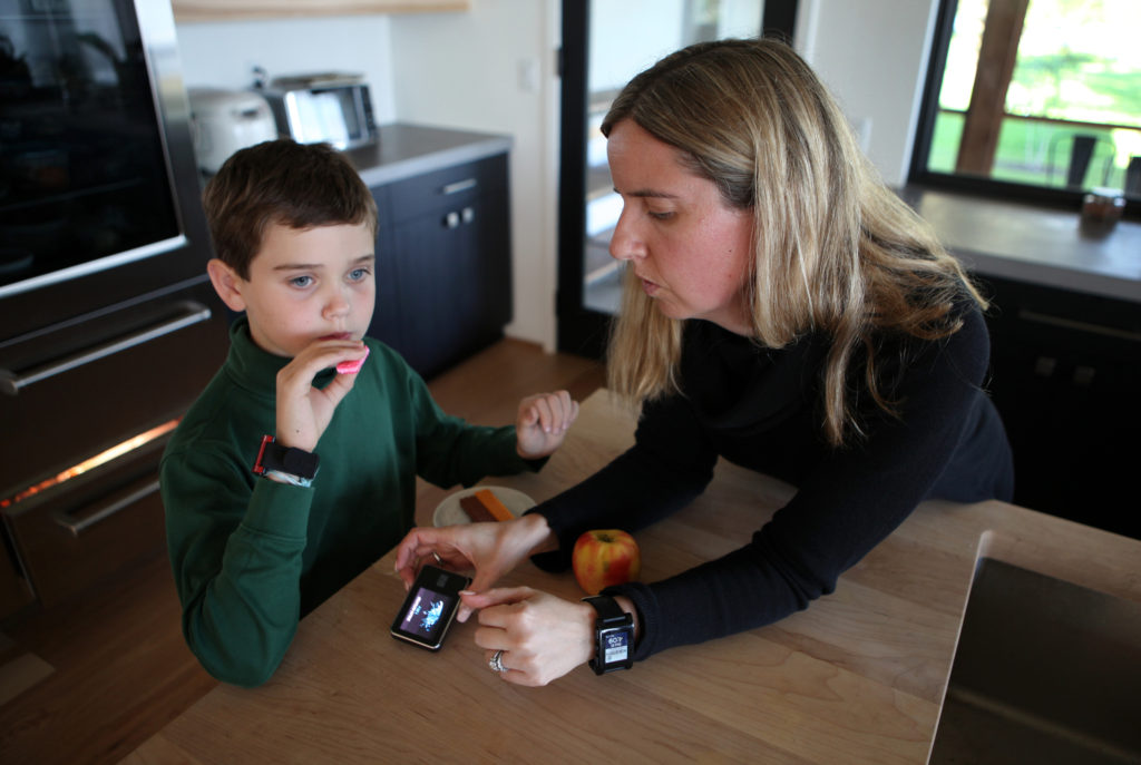 Jack Christensen has a snack of some wafer cookies and apple slices at his home in Waunakee, WI, after school on Oct. 5, 2016. His mother, Jess-Franz Christensen, logs his carbohydrate intake on a monitoring device. Both Jack's parents wear watches that can monitor Jack's blood sugar level 24-hours a day, and they are on constant vigil to make sure his numbers don't go too high or too low. Jack Christensen, 8, was diagnosed with Type 1 Diabetes at the age of 4, and requires copius amounts of medical supplies, including an insulin pump, insulin, and all related monitoring and testing equipment. His parents, Scott Christensen and Jess Franz-Christensen say that each bottle of insulin costs anywhere from $300-$400, and they use 3-4 bottles a month. They usually meet their insurance dedictible within the first few months of the year, but estimate that if they were paying out-of-pocket the supplies would run anywhere from $15K-$30K.